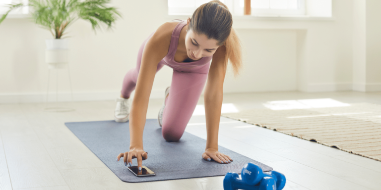 Woman on yoga mat looking at wellness app on cellphone